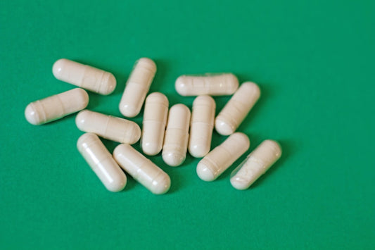 Betaine HCl capsules next to a glass of water and a beet.