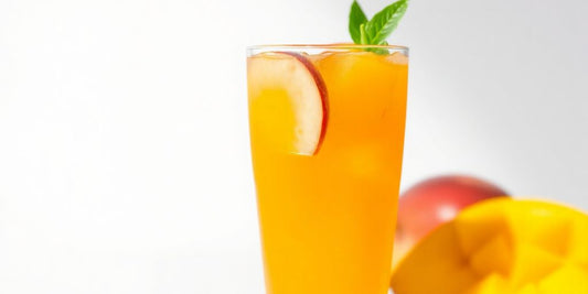 A vibrant glass of peach mango aminos with fruit.