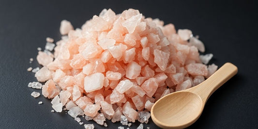 Pink salt crystals next to a wooden spoon.