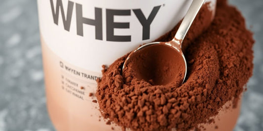 Chocolate whey protein tub with scoop and powder.