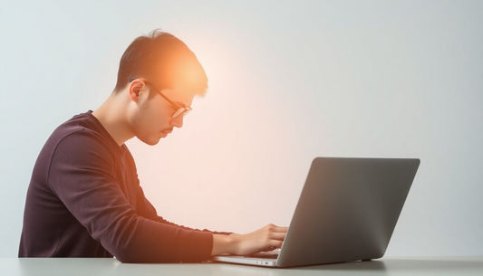 A person focused intently on a laptop, with a subtle glow around their head.